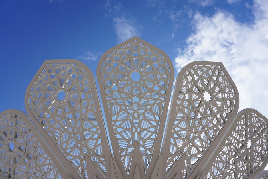 Seamless mirror wallpaper pattern — Origami by wallpaper⁶ — base photo: Elegant metal architectural design with intricate patterns set against a clear blue sky.