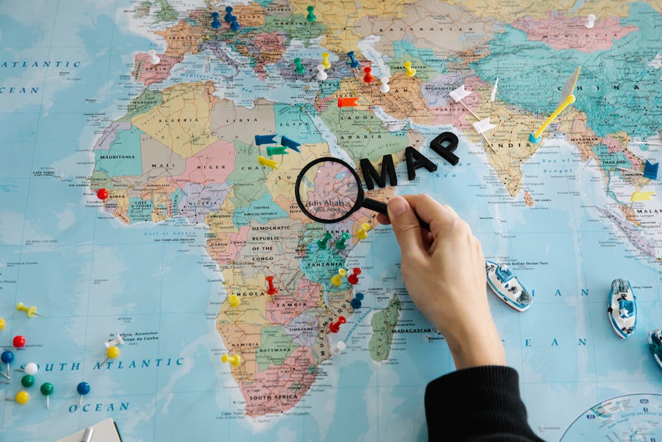 Seamless mirror wallpaper pattern — Cartography by wallpaper⁶ — base photo: Hand using magnifying glass on a colorful map, with pins and miniature boats.