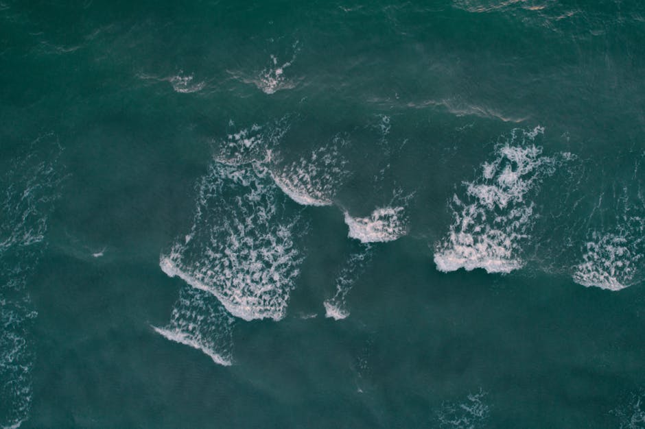 Oceanography Mirror wallpaper pattern — base photo: A serene aerial shot of ocean waves in turquoise waters, showcasing nature's beauty from above.