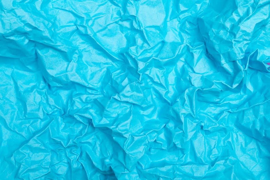 Bright blue crumpled paper texture arranged in a mirror symmetry pattern, inspired by origami art. — base photo: A close-up view of bright blue paper, artfully crumpled to create a rich, tactile texture. The subtl