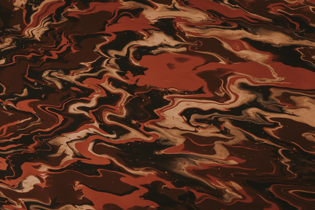 Close-up of abstract acrylic pour with swirling crimson, black, and white resembling marble, arranged in a diamond symmetry pattern. — base photo: A macro photograph captures the striking contrast and fluid movement of crimson, black, and white pi