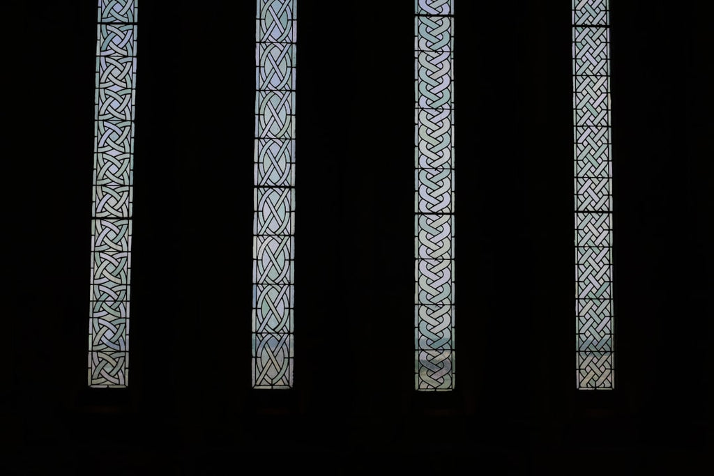 A seamless pattern resembling stained glass arranged in a kaleidoscope formation from four distinct geometric panels with intricate textures against a black background. — base photo: Four distinct panels of textured, patterned glass are presented against a stark black background. Th