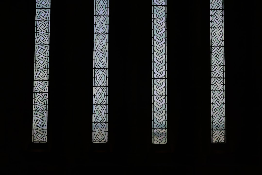 A seamless pattern resembling stained glass arranged in a kaleidoscope formation from four distinct geometric panels with intricate textures against a black background. — base photo: Four distinct panels of textured, patterned glass are presented against a stark black background. Th