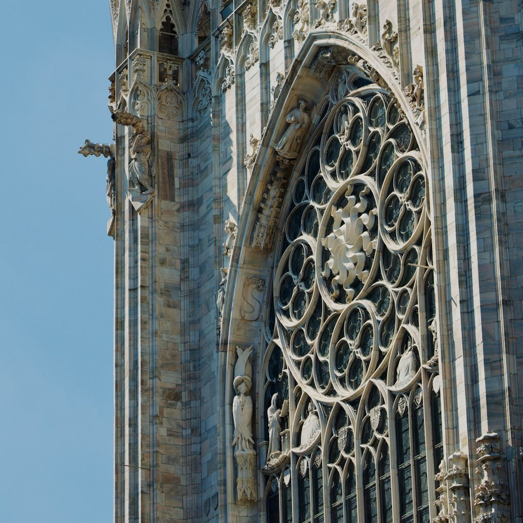 A seamless wallpaper pattern featuring rotating Gothic rose window segments in a pinwheel symmetry, showing intricate stone and glass. — base photo: A high-detail photograph by Garvit Nama capturing the intricate stone tracery and vibrant glass of a