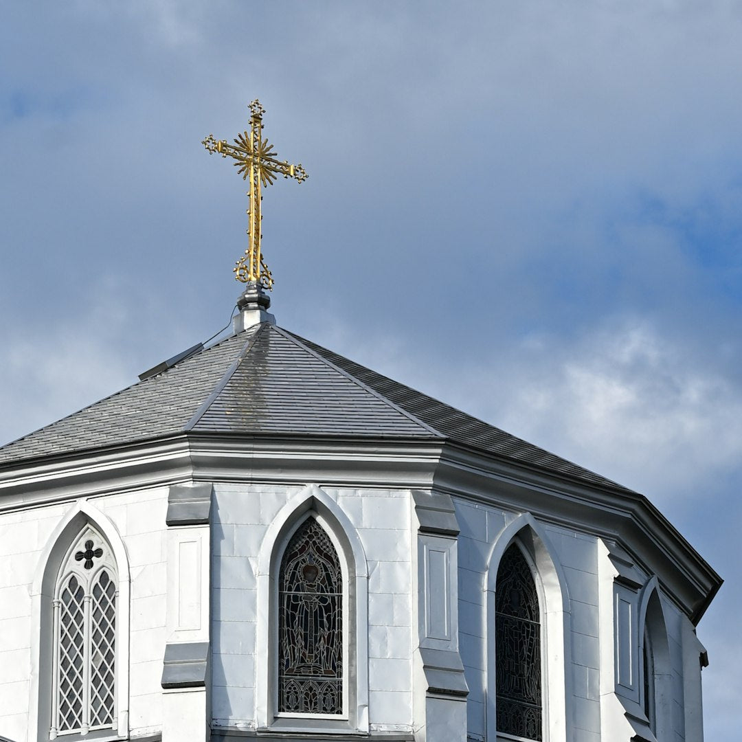 A radial kaleidoscope pattern of white steeples and golden crosses forming a blue stained glass geometric design. — base photo: A low-angle photograph by Jonathan Lim featuring a pristine white church steeple topped with a golde