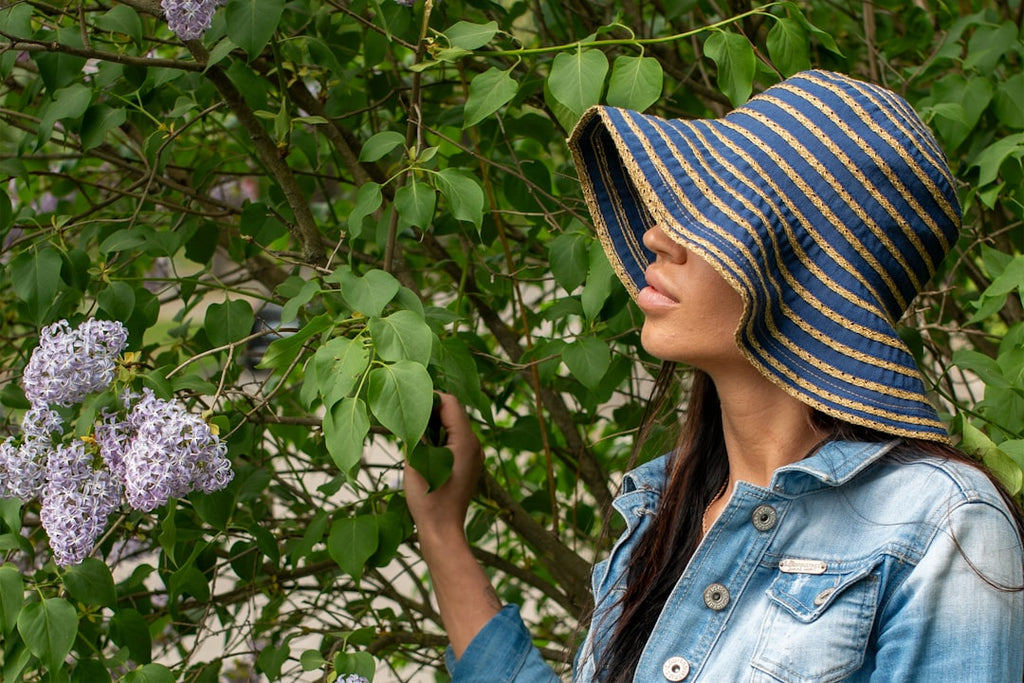 Portraits Mirror wallpaper pattern — base photo: "A young woman in a stylish denim jacket and sun hat gently smelling blooming purple lilacs in Talli