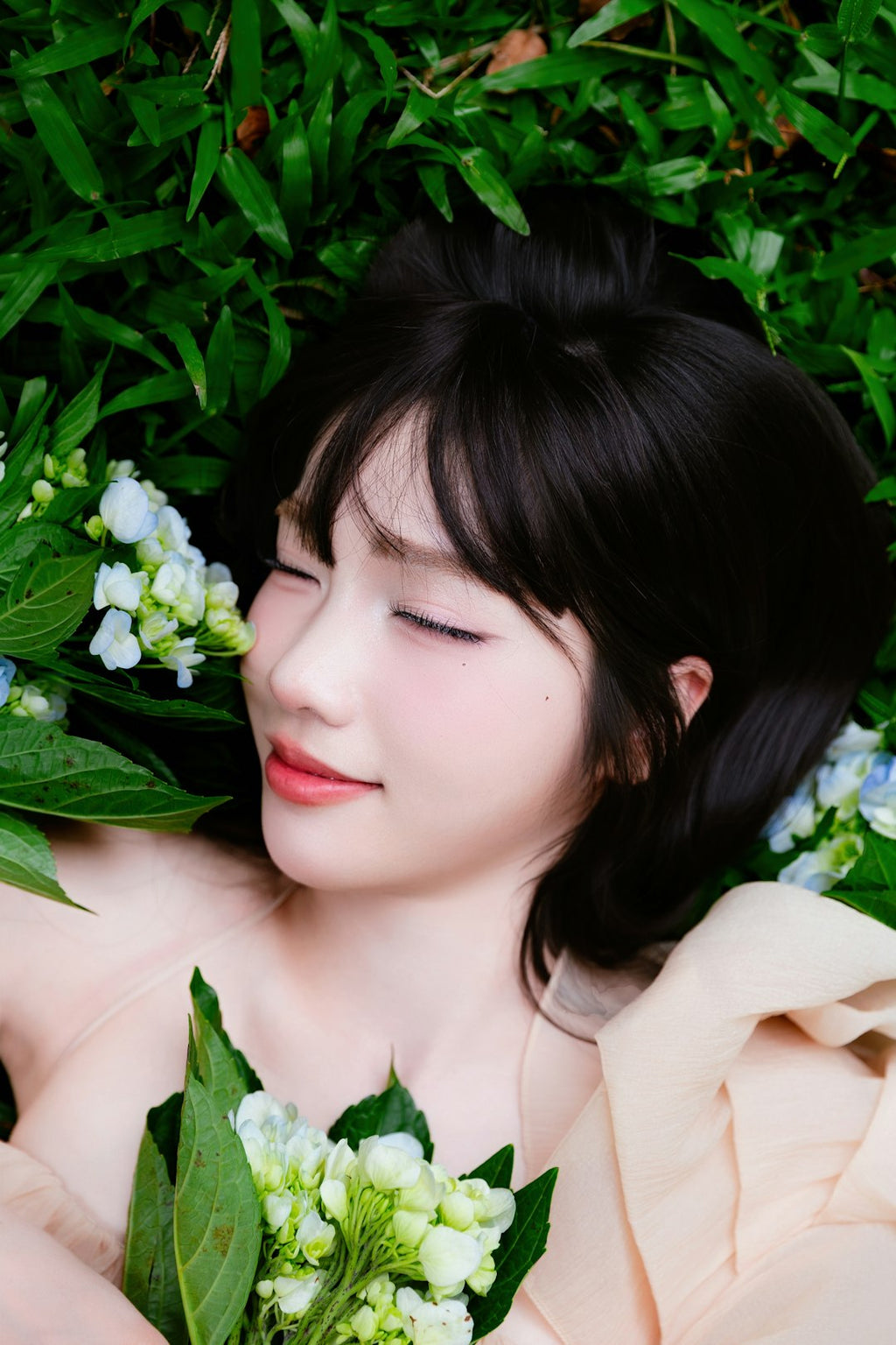Portraits Kaleidoscope wallpaper pattern — base photo: Smiling young woman lying on green grass with a bouquet of fresh hydrangea flowers, wearing a soft c