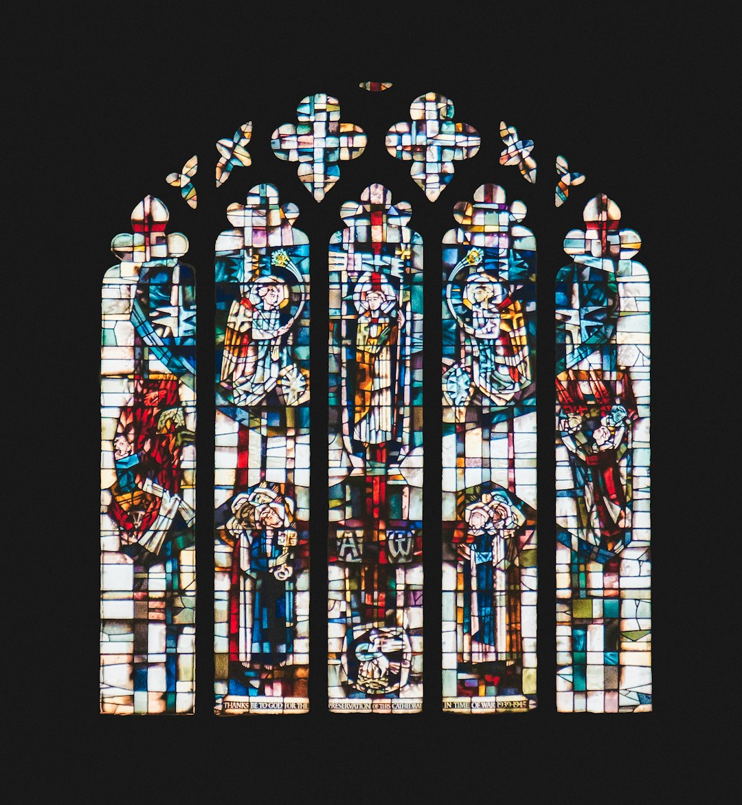 A radial Kaleidoscope pattern of blue and amber stained glass fragments with leaded borders in a complex geometric repeat. — base photo: A capture by K. Mitch Hodge of L.C. Evetts' stained-glass window, depicting the Ascension of Jesus, 