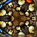 Close-up of a geometric stained glass window pattern using hexagonal symmetry, featuring vibrant colors and leaded lines.