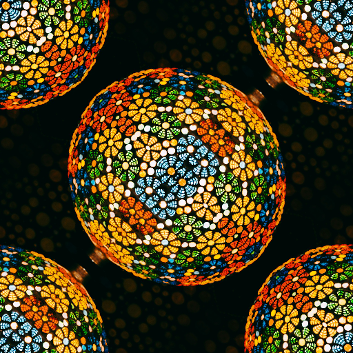 A colorful stained glass mosaic pattern arranged in a repeating diamond symmetry, featuring vibrant blue, red, and yellow shards.