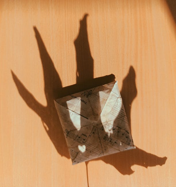 Seamless mirror wallpaper pattern — Origami by wallpaper⁶ — base photo: Origami envelope made from music sheets casting a decorative shadow on a wooden surface.