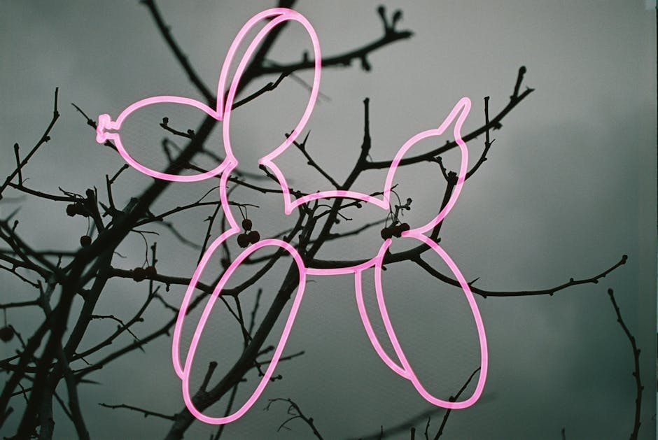 Seamless kaleidoscope wallpaper pattern — Origami by wallpaper⁶ — base photo: A pink neon balloon dog sculpture framed against barren branches and a moody sky.