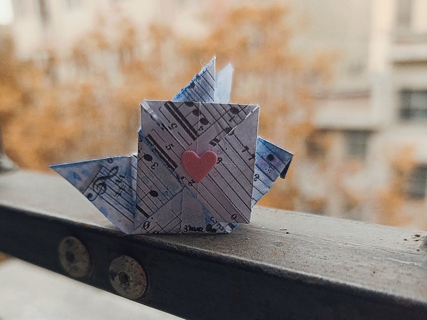Seamless mirror wallpaper pattern — Origami by wallpaper⁶ — base photo: Origami paper crane with sheet music and heart design on a ledge outdoors.