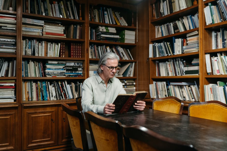 Cryptography Vertical Strip wallpaper pattern — base photo: A senior man reading at a wooden table in a cozy library filled with books.