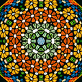 A vibrant stained glass pattern featuring radial Kaleidoscope symmetry with shards of blue, red, and orange glass.