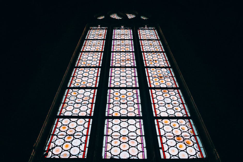 A close-up of intricate hexagonal stained glass patterns in vibrant colors, captured from a low angle. — base photo: A close-up, low-angle view of a stained glass window, revealing the intricate circular detailing and