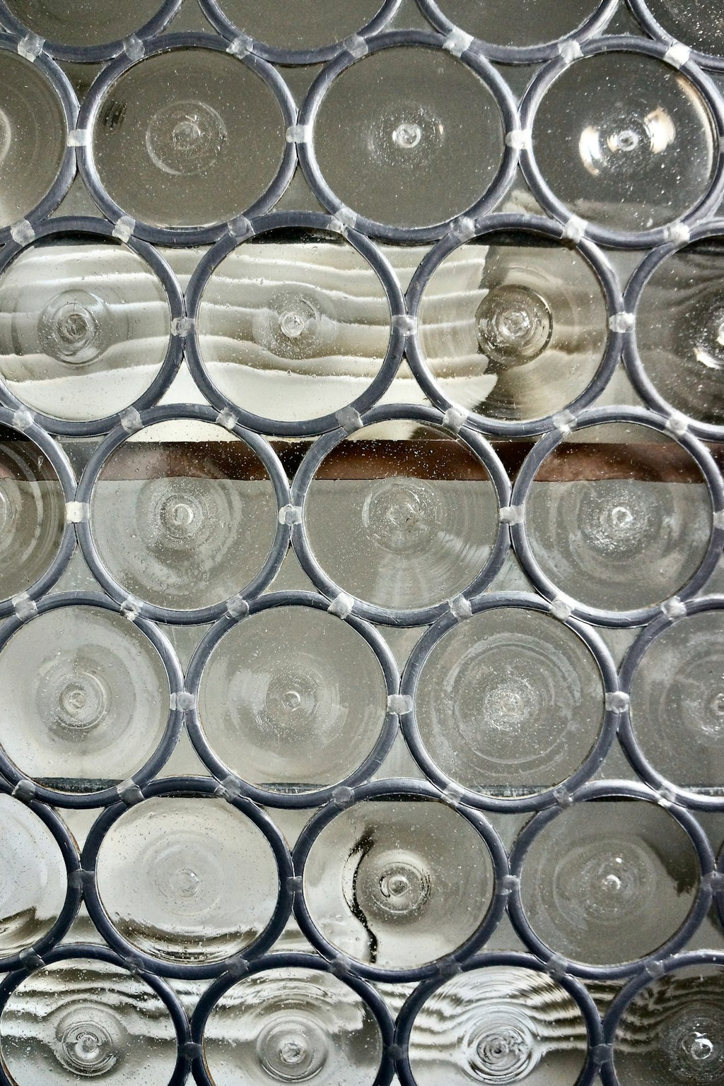 Close-up of a Leaded Glass Clusters wallpaper pattern with a hexagonal repeat, showing intricate dark metal solder lines and abstract glass fragments. Inspired by metal drum containers. — base photo: A close-up view of intricate leaded glass details. The pattern features intersecting lines of dark m