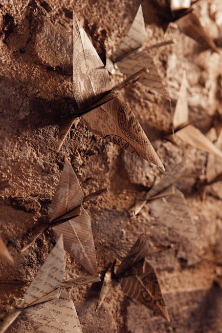 Seamless repeating pattern of origami cranes in mirror symmetry, displayed on a textured wall. — base photo: A curated collection of traditional handmade orizurus, meticulously crafted from paper, gracefully a