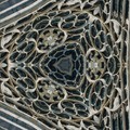 A repeating hexagonal pattern of Gothic rose window segments in red and gold stained glass with stone accents.