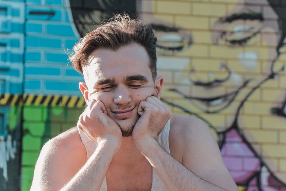 Emotions Diamond wallpaper pattern — base photo: A man with closed eyes smiles playfully against a vibrant wall mural outdoors.