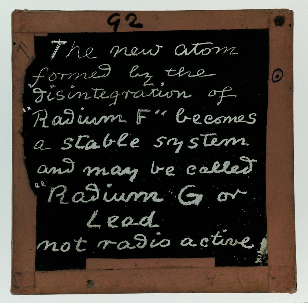 A staggered brick pattern of vintage white scientific equations and chemical notations on a dark chalkboard background. — base photo: A rare 1890-1922 lantern slide from the Clement Lindley Wragge collection showcasing handwritten sci