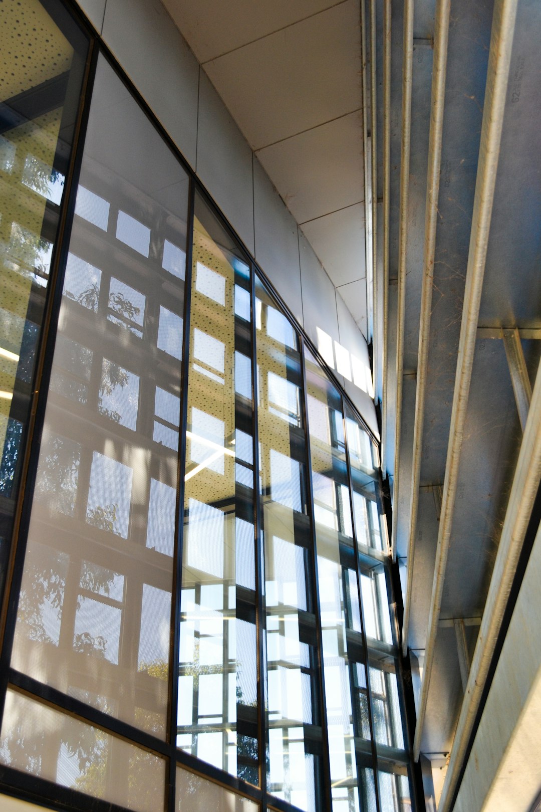 Seamless kaleidoscope wallpaper pattern — Stained Glass by wallpaper⁶ — base photo: A low-angle architectural shot of a modern glass facade. The windows reflect a grid-like interior st