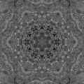 A complex kaleidoscope pattern in shades of amber and black with intricate radial symmetry and geometric facets.