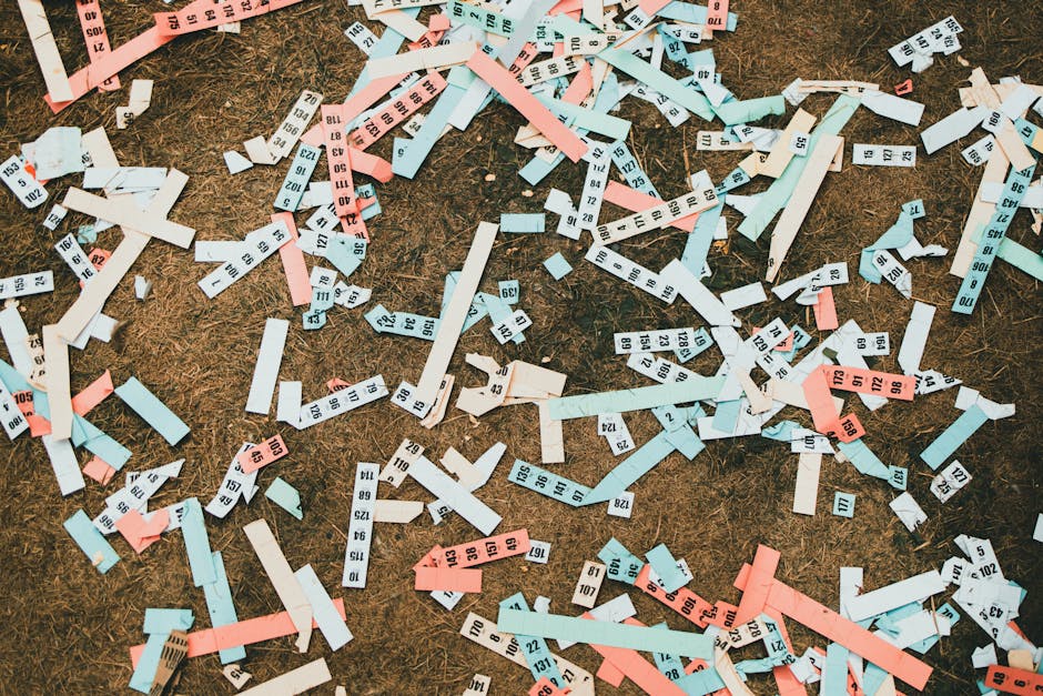 Seamless kaleidoscope wallpaper pattern — Arithmetic by wallpaper⁶ — base photo: Scattered numbered paper strips in pastel shades creating an abstract pattern on dry ground.