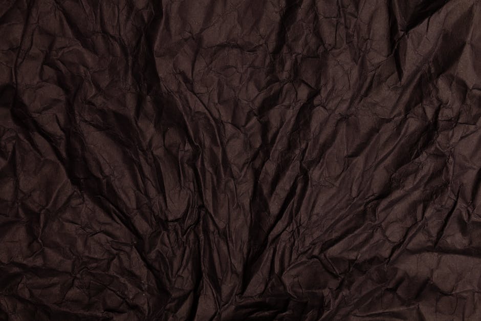 Diamond symmetry pattern resembling crumpled brown paper texture, perfect for textured wallpaper. — base photo: A close-up shot revealing the intricate texture and depth of crumpled brown paper. The lighting acce