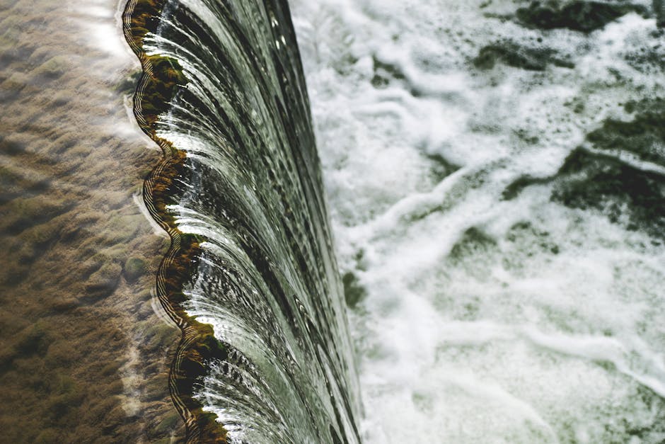 Seamless kaleidoscope wallpaper pattern — Biochemistry by wallpaper⁶ — base photo: A scenic view of a waterfall cascading over a rocky ledge, creating a textured water pattern.