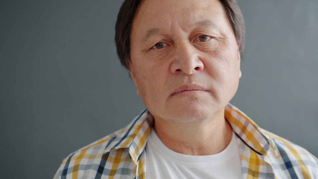 Emotions Kaleidoscope wallpaper pattern — base photo: portrait of sad Asian guy expressing shy smile looking at camera in studio standing against black ba