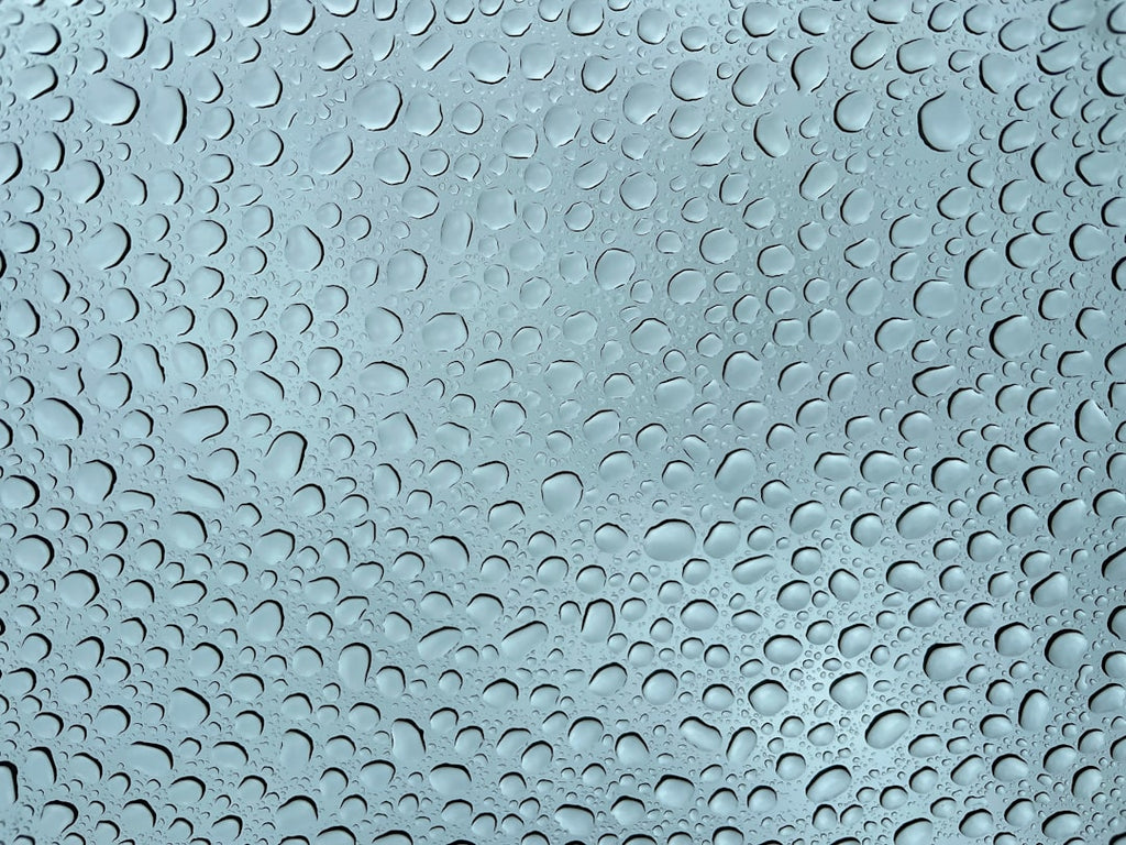 A symmetrical kaleidoscope pattern created from Borromean Rings, with a subtle texture of raindrops on glass, on wallpaper. — base photo: A close-up photograph of a windowpane covered in raindrops, where the water droplets distort and ref