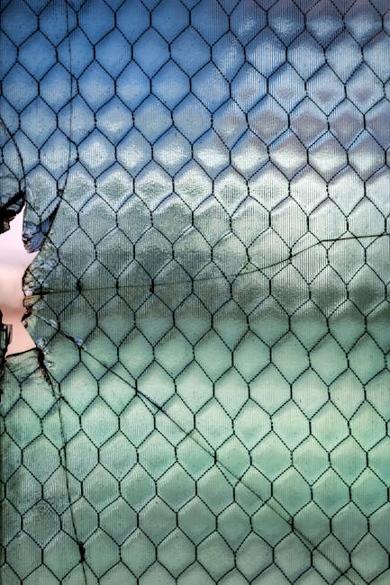 A close-up of a broken fence against a blue sky, transformed into an abstract stained glass pattern using kaleidoscope symmetry. — base photo: A close-up view of a weathered, broken fence creates an abstract pattern, set against a soft gradien